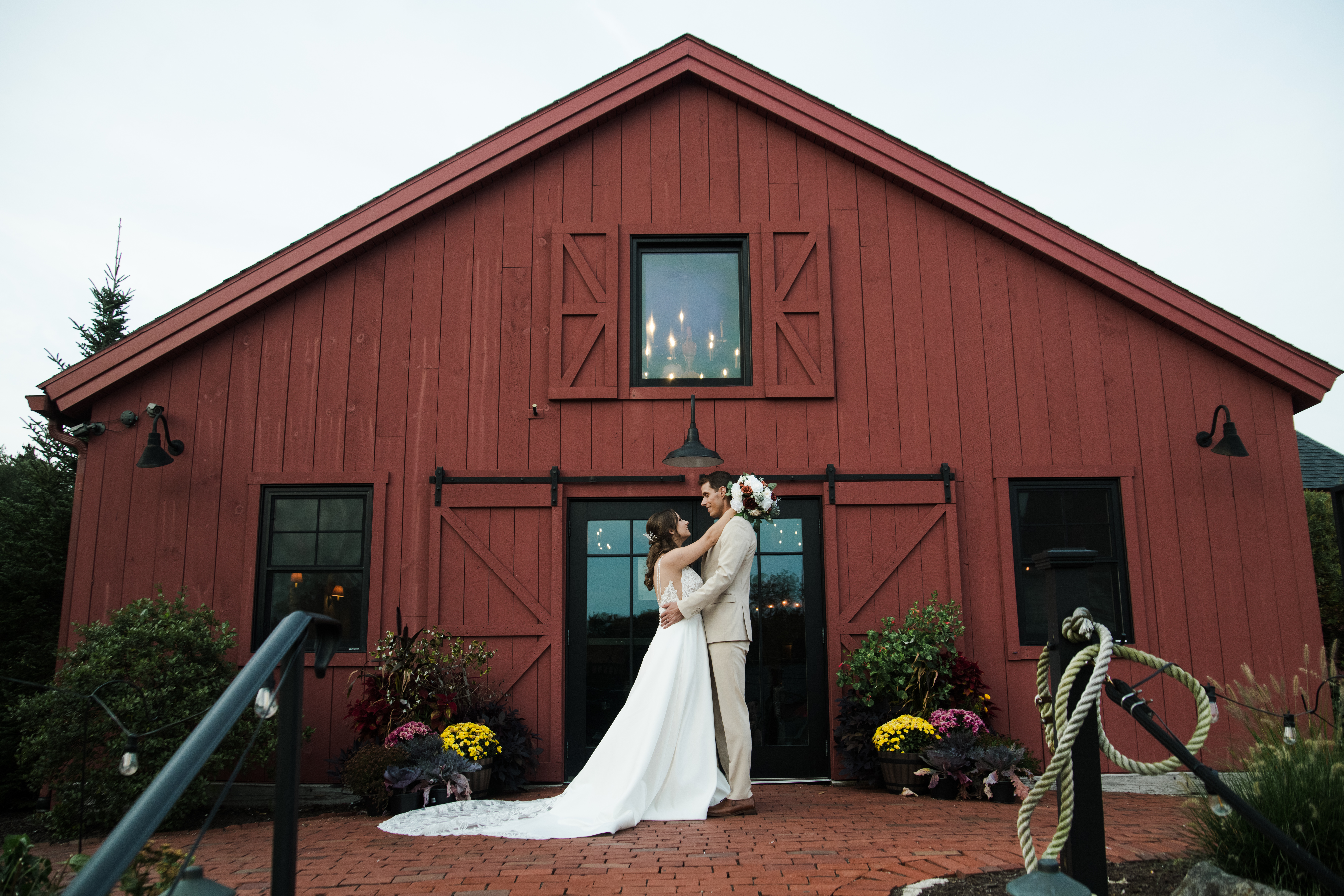 wedding couple in front of red barn looking at each other